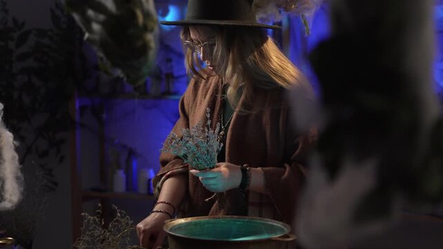 realistic witch brewing a potion. She makes a bouquet of dried herbs and recites a spell. Everyday life and traditional witchcraft. Magic and a mystical atmosphere.