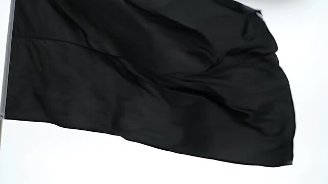 Waving Black Flag - A close-up shot of a plain black flag billowing in the wind against a bright white background.