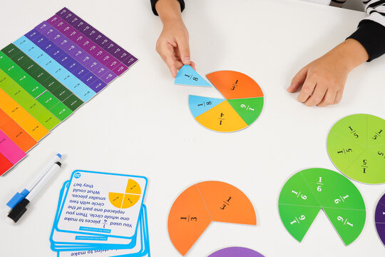 Child learns fractions by combining colorful fraction circle pieces at a table, using visual math manipulatives for a hands-on educational activity and problem solving.