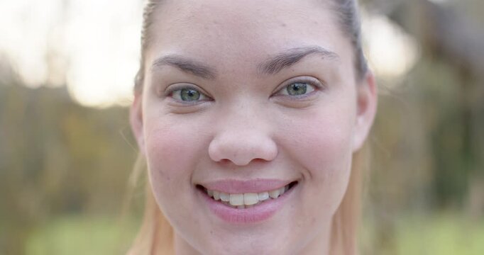 African American woman holding gaze while camera pulling back at park, revealing shoulders, smiling