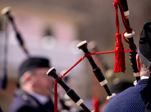 Close-up of Scottish bagpipes with a red cord and tassel played at a funeral, representing mourning, remembrance, tribute and traditional ceremonial music with no face visible.