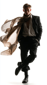 Editorial fashion portrait of handsome man with billowing scarf for an autumn menswear streetwear concept, capturing male model in blazer and combat boots on white background.