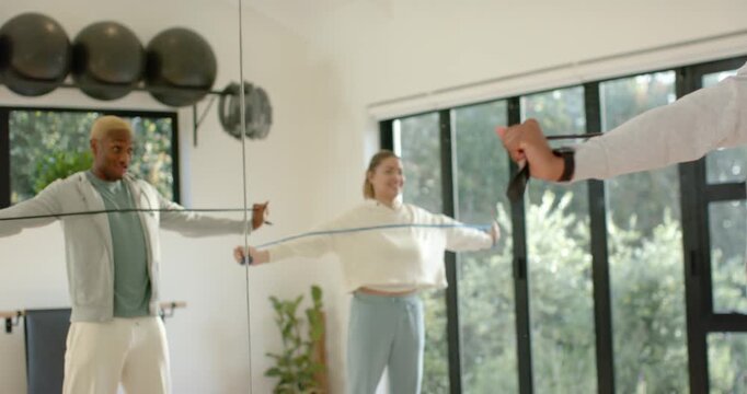 African American couple entering gym mirror, steadying bands, checking posture, pulling reps