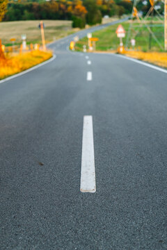 Winding Road with White Lane Markings Through Autumn Landscape