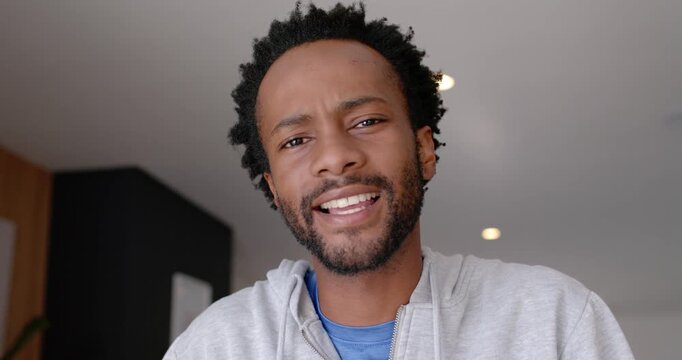 African American man starting with frowning wearing hoodie explaining to viewer at home smiling
