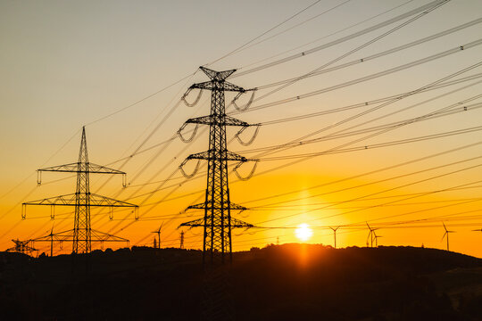 Electricity Transmission Pylons and Wind Turbines at Sunset