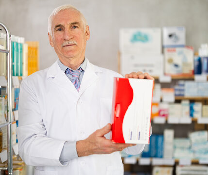 Elderly male pharmacist offers box with medical device