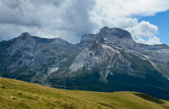 serene mountain peak standing tall in rugged landscape with grassy foreground and cloudy sky from a lower vantage point looking up at the majestic nature photography destination.