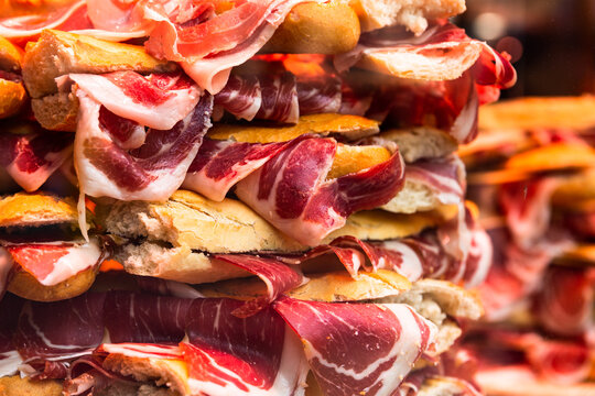 traditional Spanish bocadillos with Iberico jamon laid out in a slide on a shop window