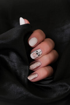 A beautiful oval-shaped Christmas manicure against a black background. A winter trend featuring beige gel polish (Shellac). Space for text.