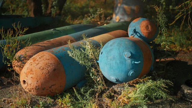 Obsolete, abandoned, and rusty combat missiles and shells stand amidst the natural landscape. A weapons graveyard. An echo of war.