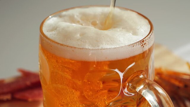 Close-up of freshly poured light lager beer in a frosty glass mug covered with condensation. Cold refreshing alcoholic drink with creamy foam head, bar and beverage concept. High quality 4k footage