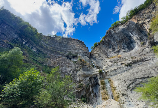  a river in the middle of cliffs with trees under a blue sky 