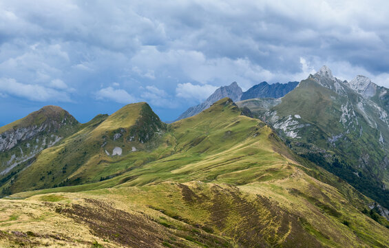 serene mountain landscape with majestic peaks and wide-angle perspective from a distance in a natural outdoor setting with green grass and gray rocks, travel and adventure.