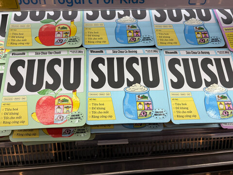Colorful yogurt packs for kids are displayed in a fridge. The packaging features playful designs with illustrations of fruit. The brand name 'SUSU' is prominently featured.