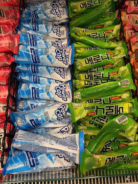 A colorful assortment of frozen ice treats displayed on a store shelf. The image features blue and green packaging with Korean text. The vibrant colors attract attention.