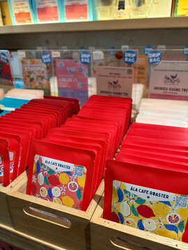 A display of colorful coffee packaging in a retail store. The focus is on red bags featuring various designs, arranged neatly. 