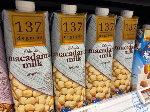 Four cartons of 137 Degrees original macadamia milk on a supermarket shelf. The packaging features a white background with a minimalist design and images of macadamia nuts. 