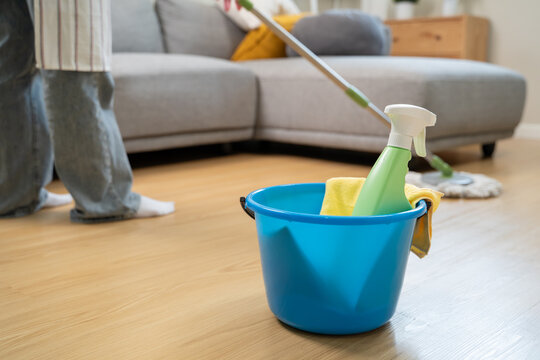 Housekeeper mopping the laminate wooden floor and cleaning dust during chores daily routine.