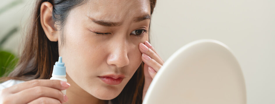 asian young woman using medical eye drops to treat dry eye and irritation.