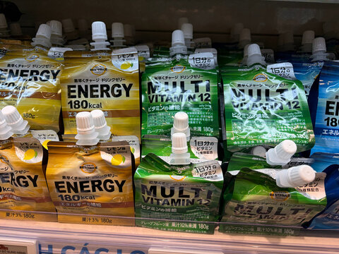 Various flavored health drink pouches lined up on a shelf. Bright colors include yellow for energy drinks and green for multivitamins. Compact design for easy portability.