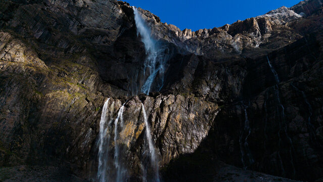 Cirque de Gavarnie beautiful waterfall with river underneath high cliffs, Pyrenees Mountains, France 