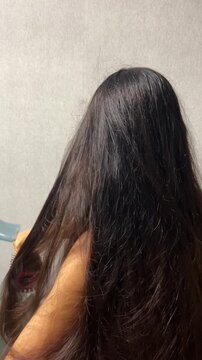 Woman drying her long hair with a hair dryer at home during a daily hair care and beauty routine