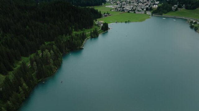 Aerial drone view of alpine lake town in mountain valley pine forests cloudy Switzerland