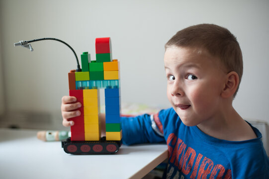 Happy young boy shows his creative spirit while building a colorful tower with blocks at home during a peaceful afternoon of play and fun
