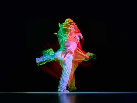 Street dancer captured during high kick pose with colorful motion trails. Concept of dance competitions, creative banners, club promotions and digital layouts.