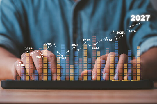 Financial growth forecast to 2027 with business professional typing on keyboard and rising data chart representing market trends, economic outlook, investment analysis and long-term business growth.