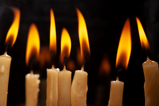 Candles burning with flames in a dark setting during a ceremony or event