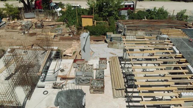 High-angle construction site with timber beams, steel reinforcement, and concrete slabs under bright daylight