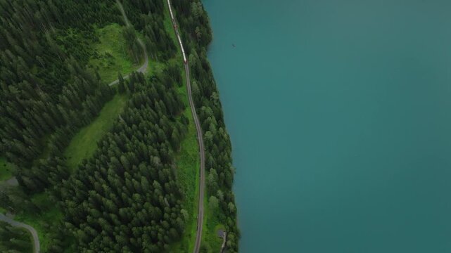 Aerial drone view of alpine lake town in mountain valley pine forests cloudy Switzerland