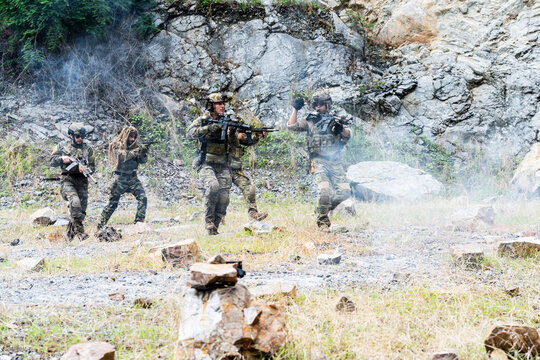 Military training exercise in a rocky terrain with soldiers performing various actions in the field