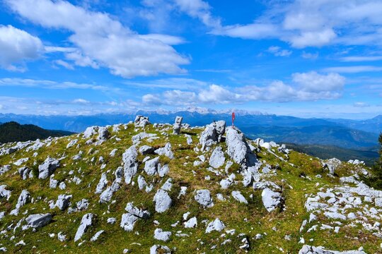 Rocky terrain at the top of Kosmati vrh with a view of Triglav mountain in Julian alps in the distance in Gorenjska, Slovenia