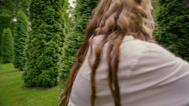 Diverse teenagers wearing scary Halloween costumes and makeup running through hedge maze outdoors in slow motion. Clip ideal for holiday marketing and youth event advertising