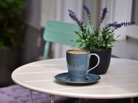 Rustic Speckled Blue Ceramic Coffee Cup on White Bistro Table with Potted Lavender Plant on a Cozy Terrace