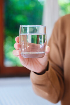 Vertical closeup image of a woman holding a glass of drinking water