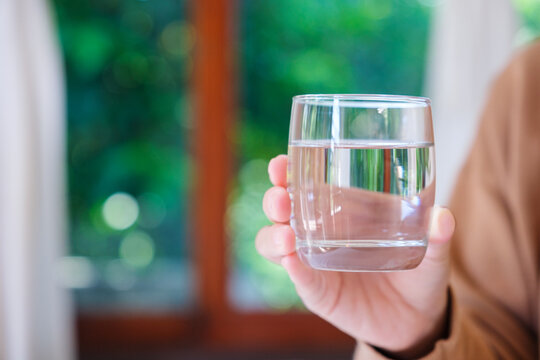 Closeup image of a woman holding a glass of drinking water