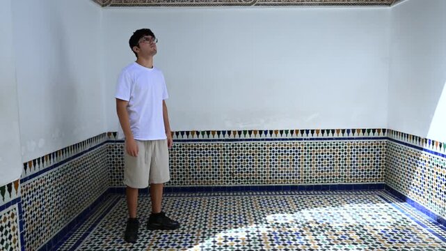 Marrakech, morocco. August 10, 2026. Tourist man standing inside a room of the bahia palace in marrakech, morocco, admiring the intricate and colorful zellige tilework