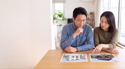 Obraz premium 二種類の住宅写真を見比べる夫婦とコピースペース