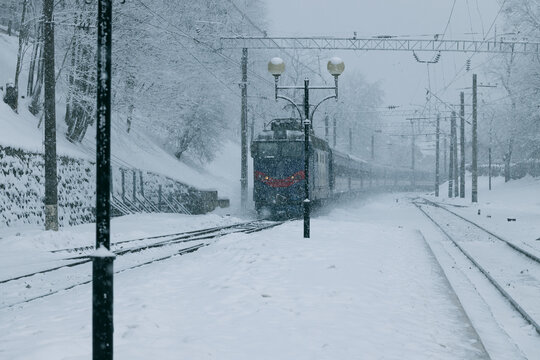 A passenger train travels through a snowy landscape on a cold winter day in the countryside