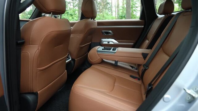The second row of the beige SUV, featuring an open armrest.