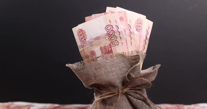 sack of money containing 5,000-ruble banknotes as a background; a display of Russian currency
