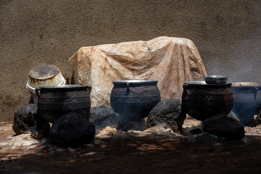 Blackened cauldrons steam over hot coals during traditional shea butter processing, Savanes district, Tcheregnimin, Ivory Coast