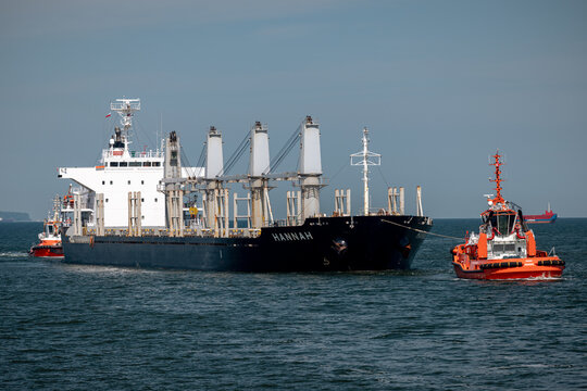 Gdansk, Poland - July 14, 2026: Tugboats escort a large commercial cargo vessel near the entrance to the Port of Gdansk.