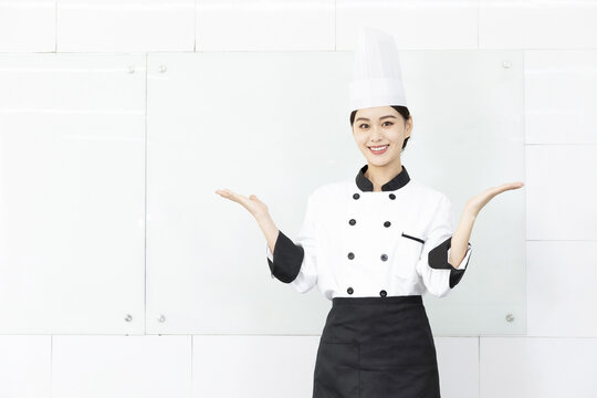 Smiling Female Chef in White Uniform Presenting with Open Hands