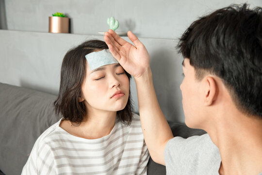 Caring man checking temperature of sick woman with fever at home