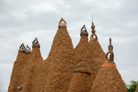 A row of ceramic-capped pinnacles rises against green foliage at the 17th-century Sudano-Sahelian mosque, Savanes district, Kouto, Ivory Coast